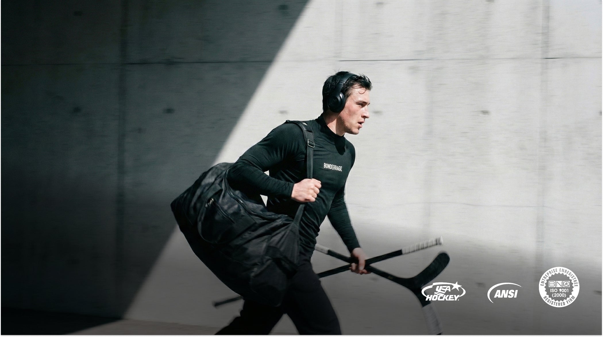Hockey athlete wearing a Bonderkage cut-resistant base layer, carrying equipment and running through a concrete tunnel.